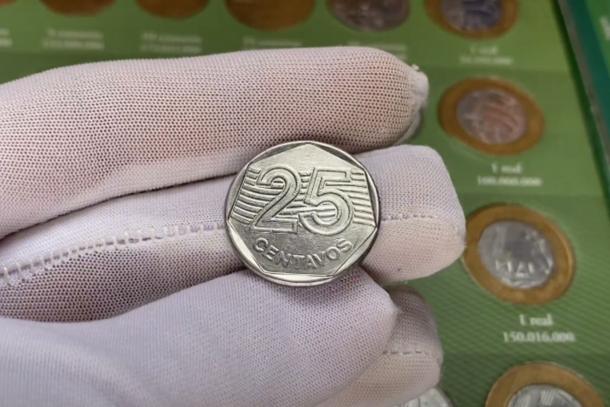 Uma moeda de 25 centavos na mão de uma pessoa (com luva branca)