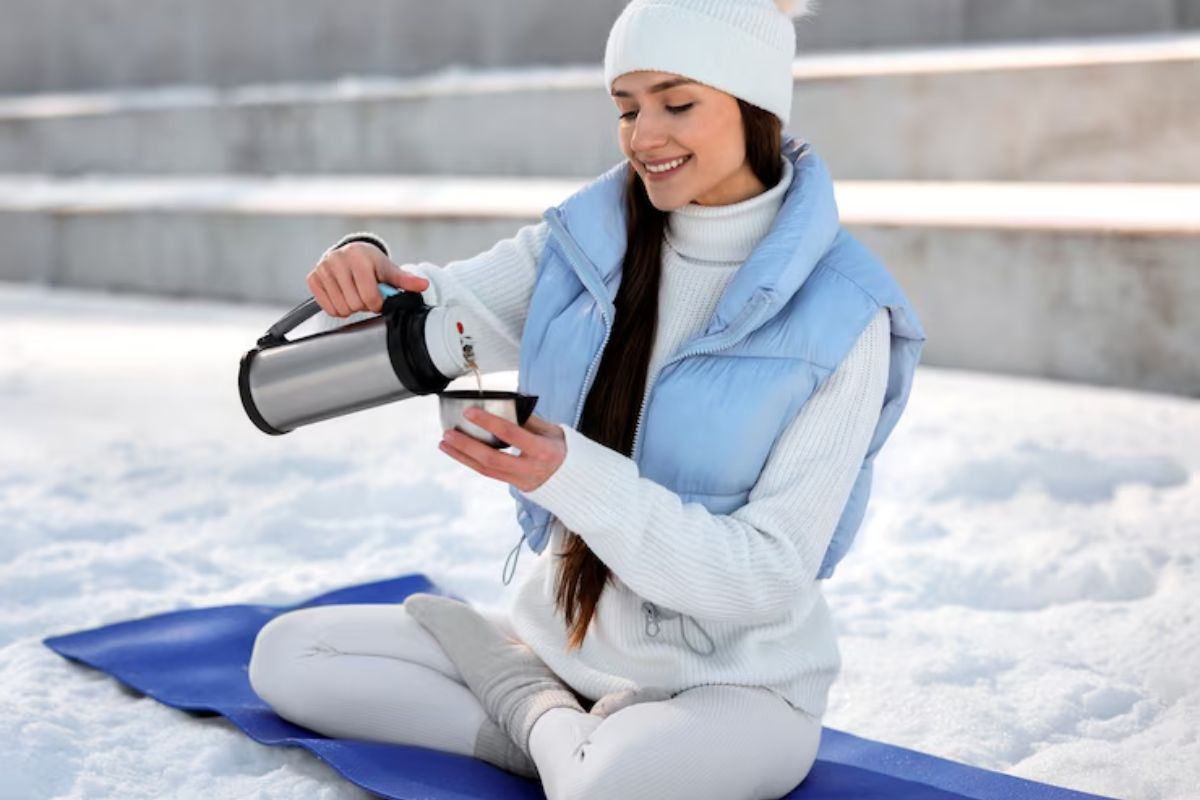 Uma mulher na neve bebendo um dos 5 chás milagrosos para a imunidade