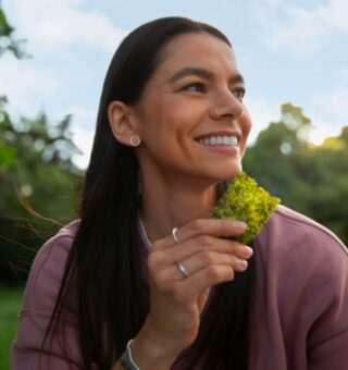 Uma mulher comendo o Vegetal que aumenta a felicidade