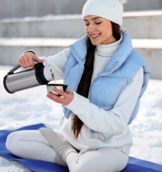Uma mulher na neve bebendo um dos  5 chás milagrosos para a imunidade