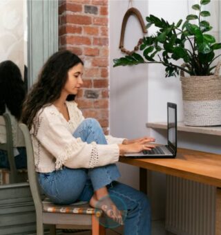 Uma mulher sentada na sala da sua casa procurando uma das 5 ideias de renda extra