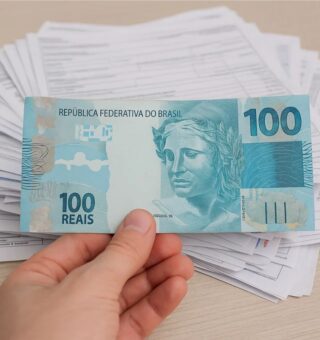 Uma pessoa segura uma nota de R$ 100 para limpar seu nome
