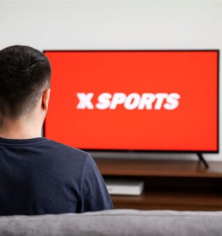 Um rapaz na sala da sua casa vendo a abertura do Xsports