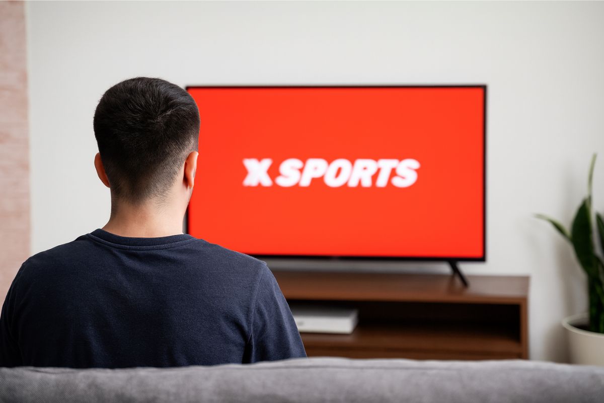 Um rapaz na sala da sua casa vendo a abertura do Xsports