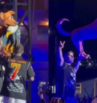 MC Hariel em cima do palco com o cachorro caramelo mordendo a águia (símbolo norte-americano)