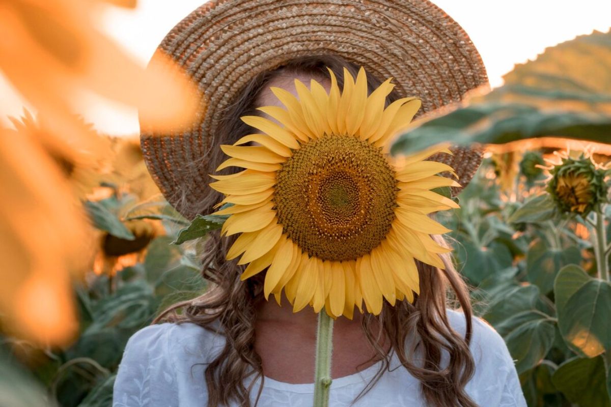 Uma mulher seguira um girassol cobrindo seu rosto, representando a Primavera
