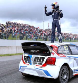 Um corredor de Rallycross em cima do seu carro comemora a vitória