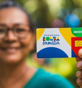 Uma mulher segurando o cartão do Bolsa Família
