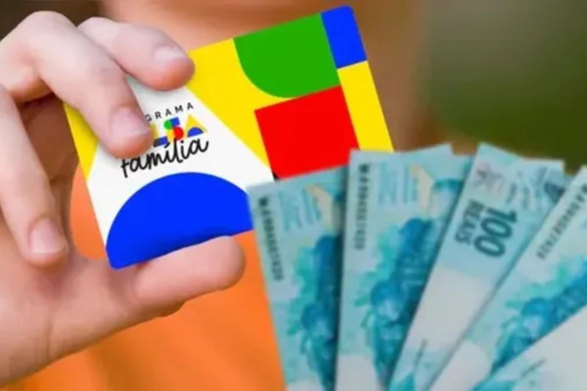 Uma pessoa segura o cartão do Bolsa Família e notas de R$ 100