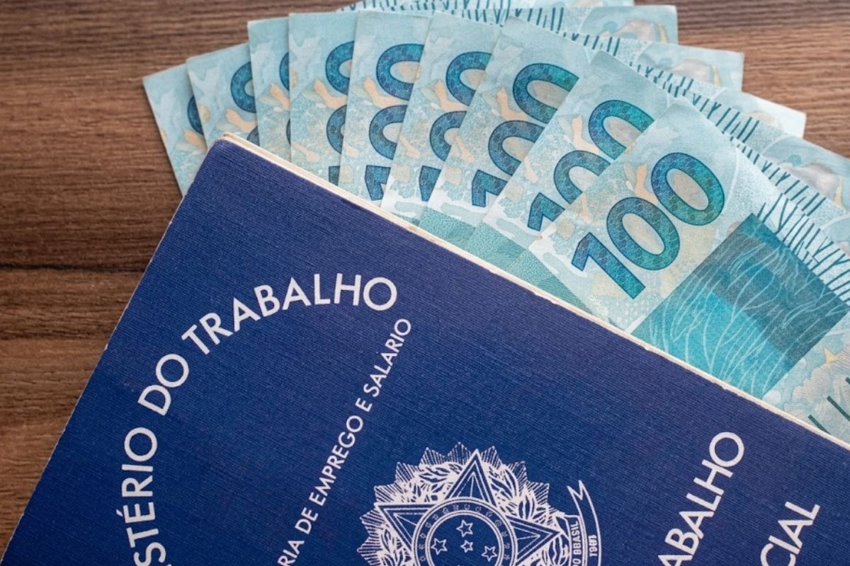 Carteira de trabalho junto com notas de R$ 100
