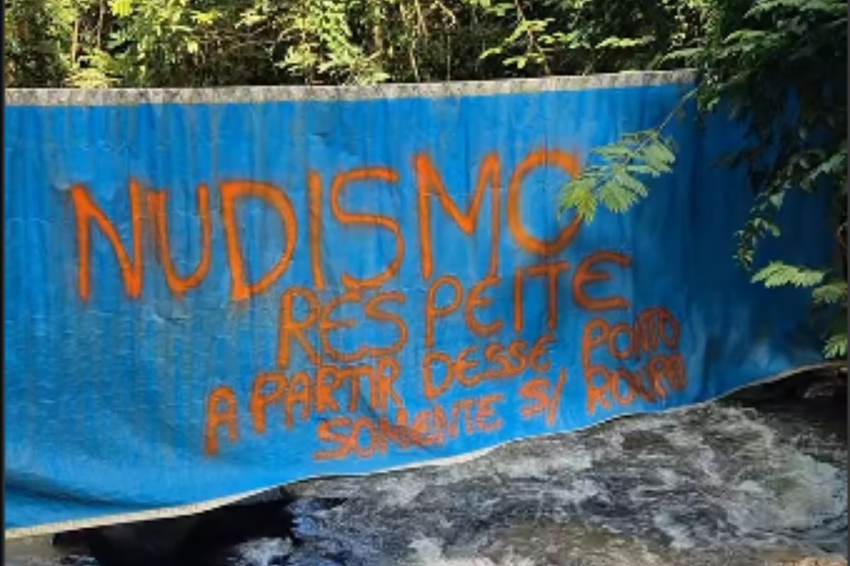 Um aviso escrito em pano avisando sobre o início da cachoeira do nudismo