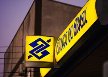Notas de R$ 50 ao lado de um app do Banco do Brasil no celular, na mão de uma mulher