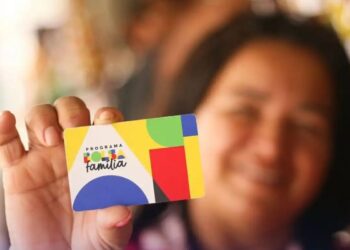 Uma mulher segurando o cartão do Bolsa Família