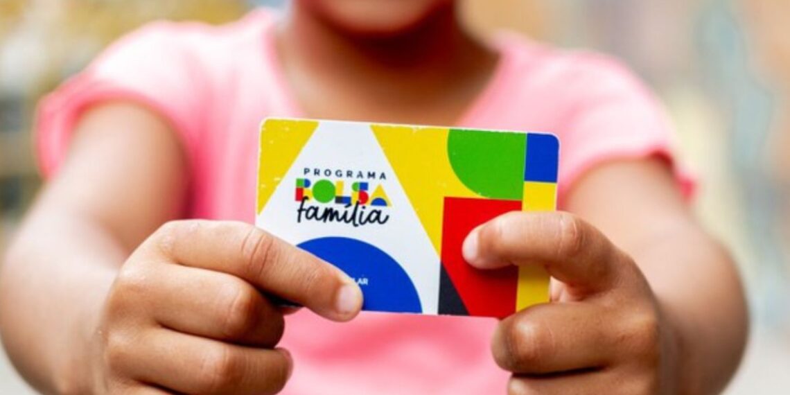 Uma criança segura o cartão do Bolsa Família