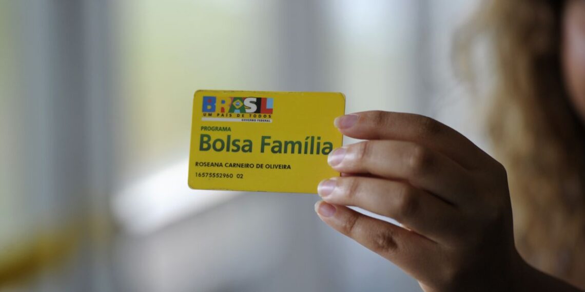 Uma mãe segura o cartão do Bolsa Família