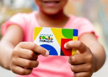 Uma criança segura o cartão do Bolsa Família
