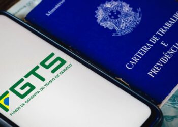 Aplicativo do FGTS ao lado de uma carteira de trabalho